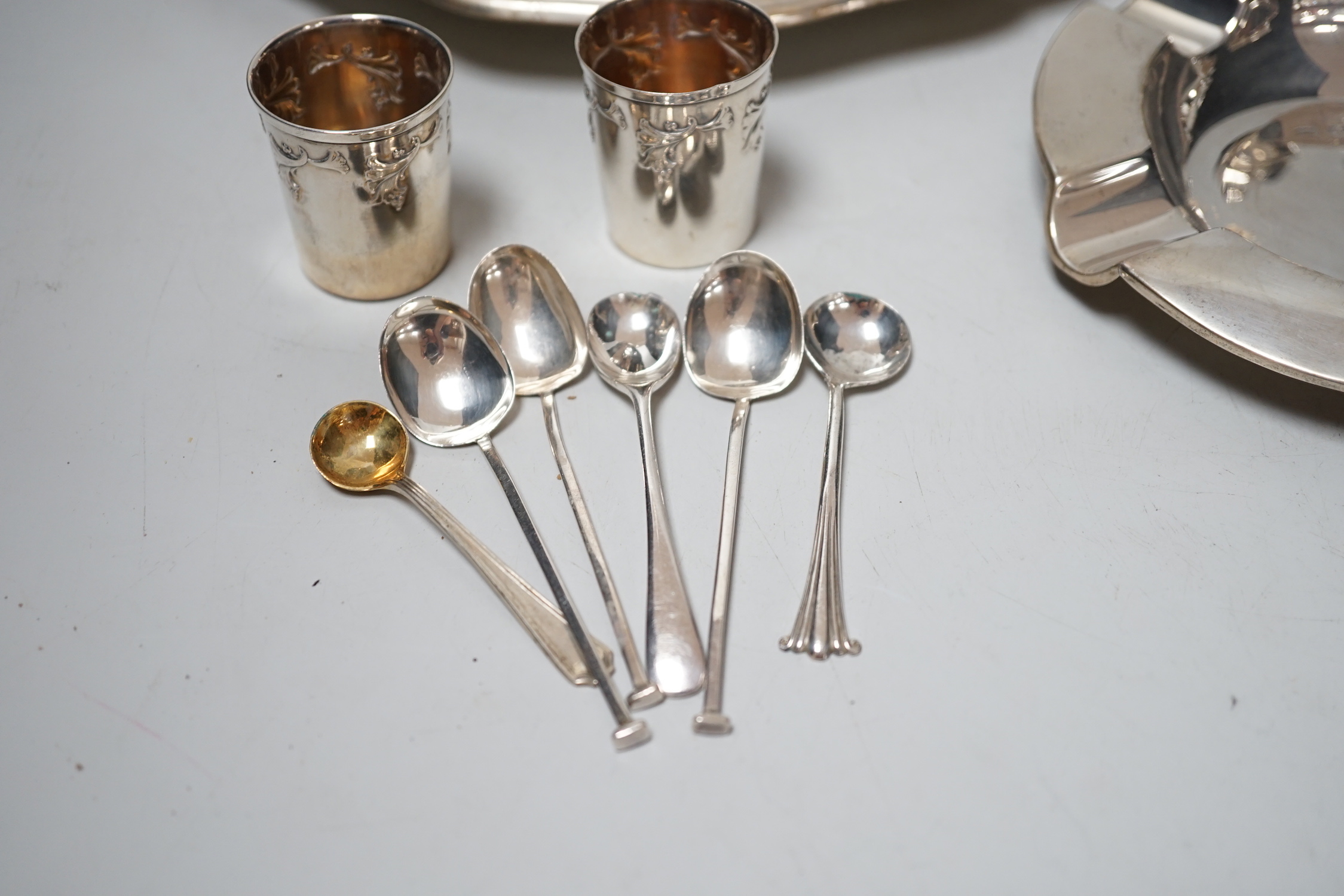 An 800 white metal plate, 24.8cm, a George V silver two handled bowl, a silver ashtray, six silver condiments, two 800 tots and minor plated ware, 24.1oz.